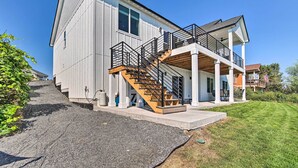 Ein modernes, zweistöckiges Haus mit einer Veranda, einer Holztreppe und einem großen Vorgarten.