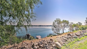 Blick auf einen See mit Steg, Felsen und Bäumen.