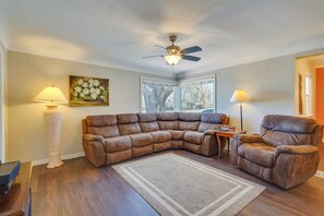 A living room with a sectional sofa, two floor lamps, a ceiling fan, and a painting on the wall. - Pueblo House by Riverwalk, 2 Miles to Fairgrounds! (Pueblo)