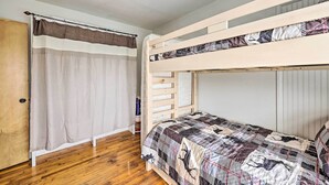 A bunk bed room with a wooden floor, a curtain, and a door. - Pet-friendly Cabin Rental Retreat! (Keota)
