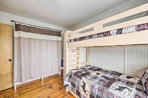 Dormitorio con literas, suelo de madera, cortina y puerta.