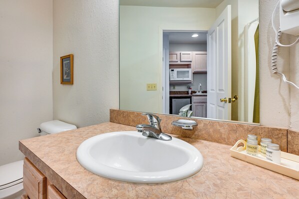 A bathroom with a white sink, a mirror, and a vanity with a tray holding toiletries. - Close to Saginaw Bay Waterfront! Pigeon Studio (Pigeon)