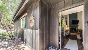A wooden cabin with a welcome sign, a fireplace, and a TV in the living area. - 'moondance' Ruidoso Retreat w/ Hot Tub & Views! (Ruidoso)