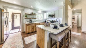 A modern kitchen with white cabinets, a central island, and wooden flooring. - 'moondance' Ruidoso Retreat w/ Hot Tub & Views! (Ruidoso)
