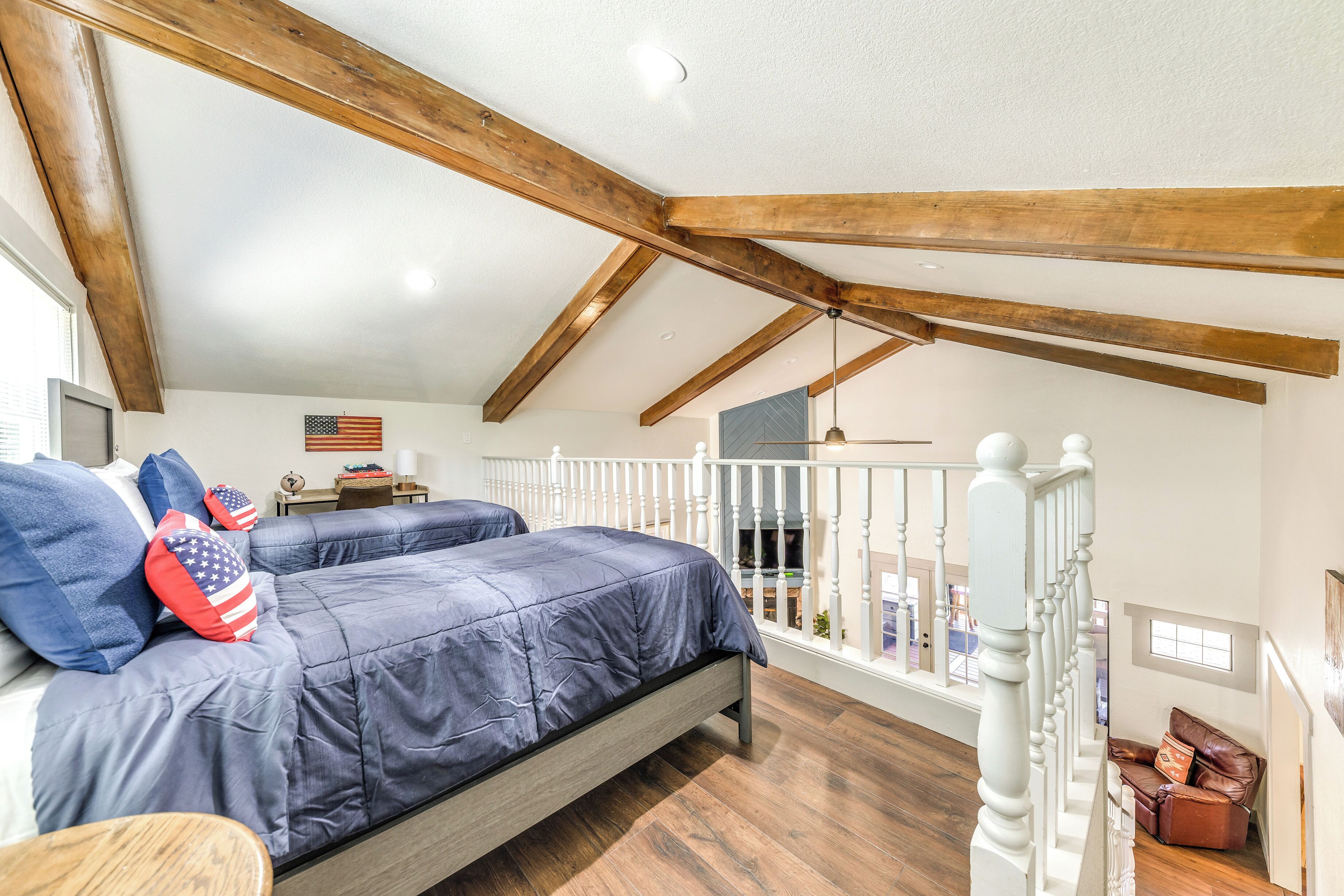 A bedroom with a bed, a desk, and a balcony with a railing.