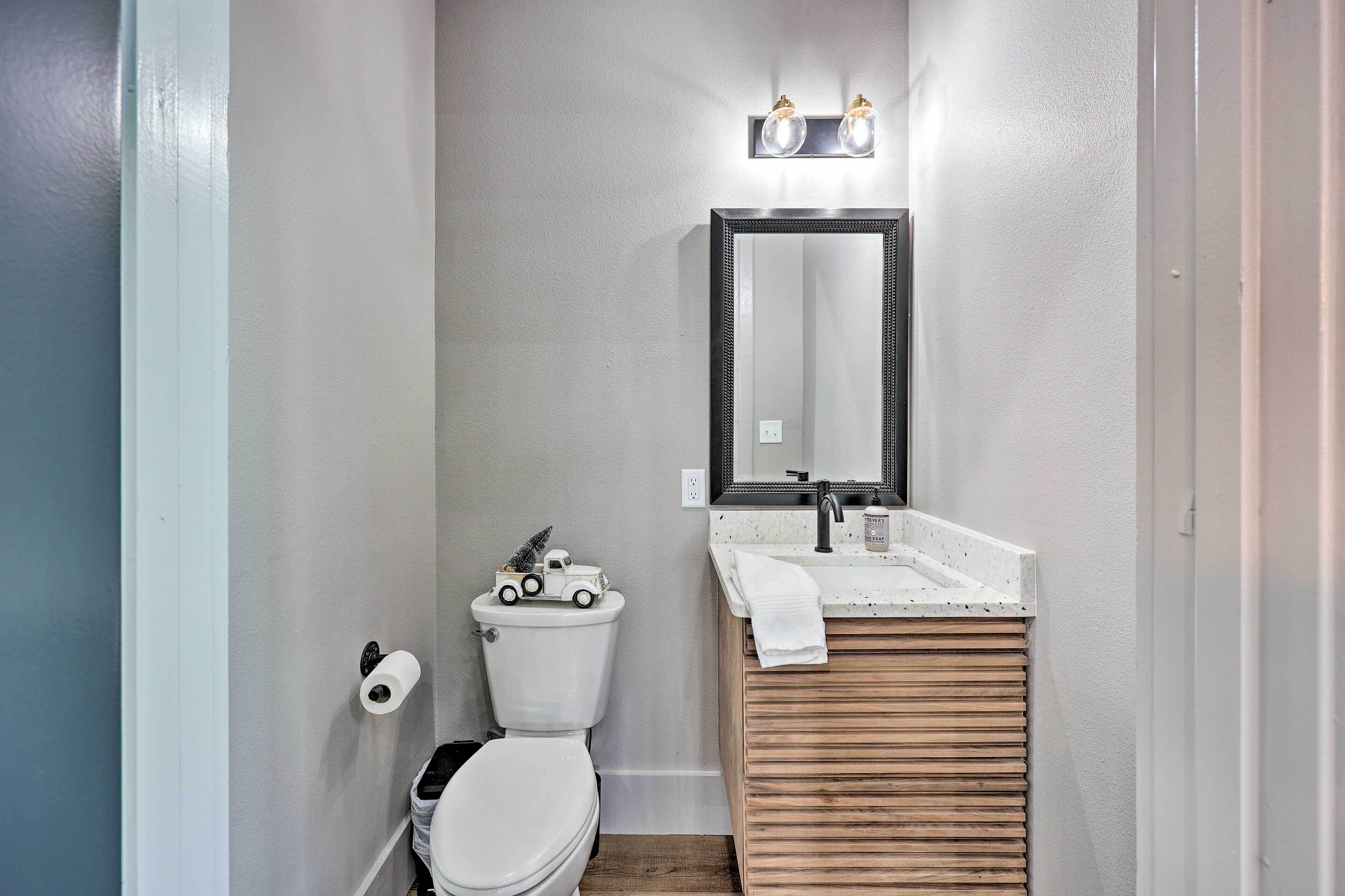 A compact bathroom with a toilet, a sink with a wooden vanity, and a mirror above the sink.