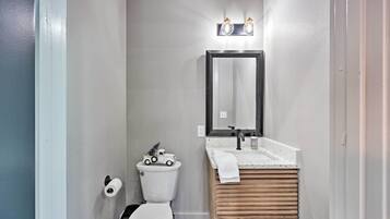 A compact bathroom with a toilet, a sink with a wooden vanity, and a mirror above the sink.