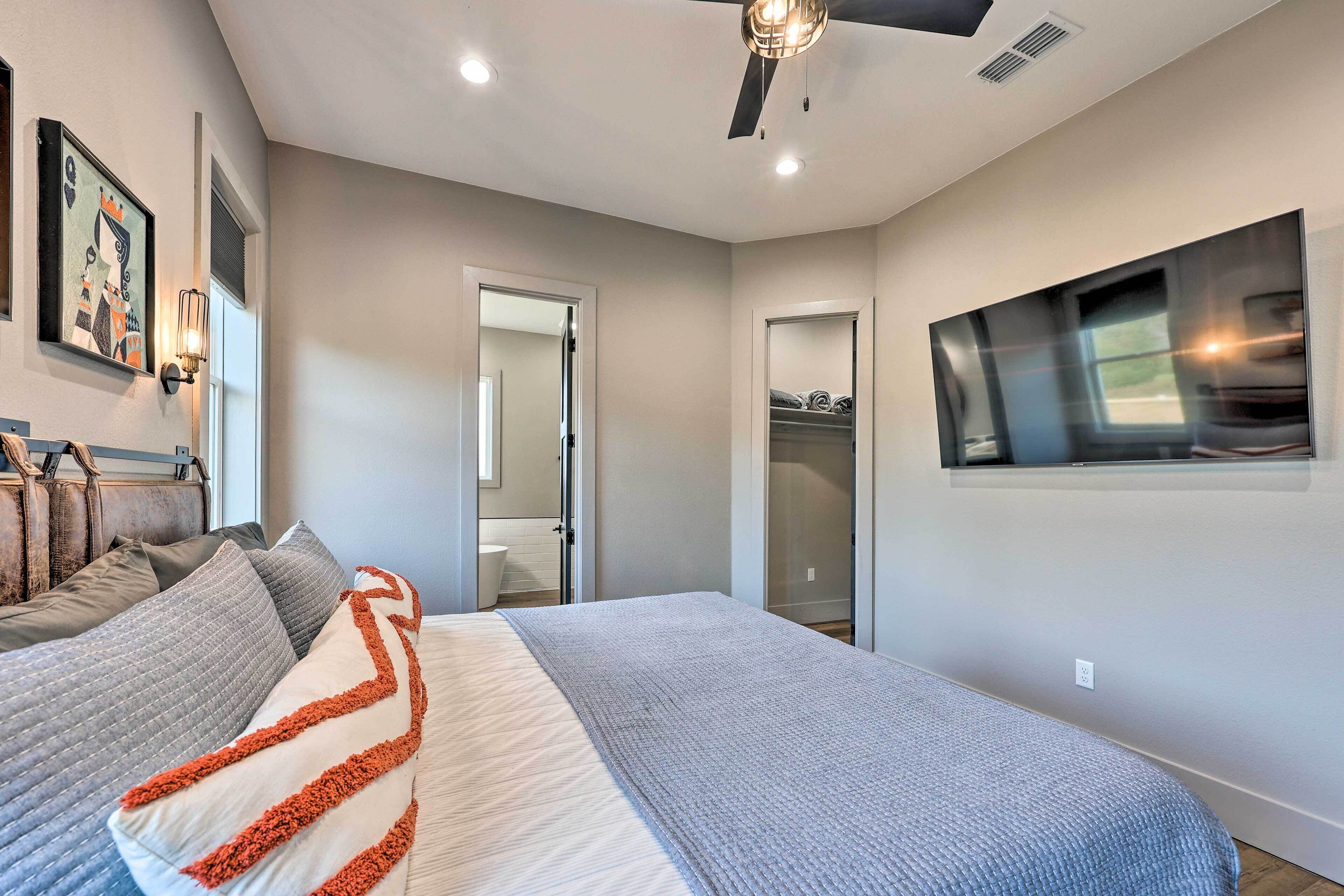 A bedroom with a bed, a ceiling fan, a large window, and a closet.