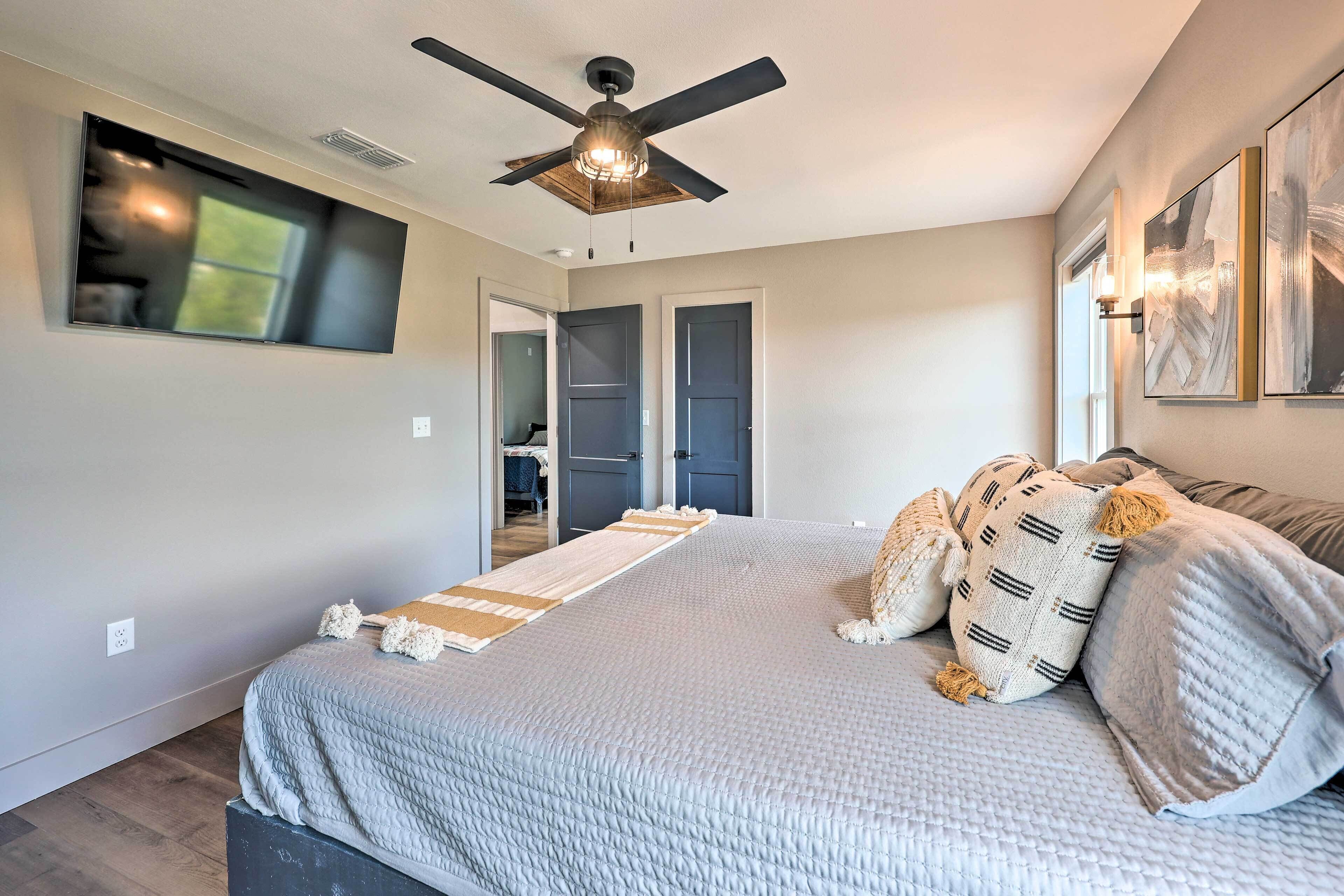 A bedroom with a bed, a ceiling fan, a window, and a door.