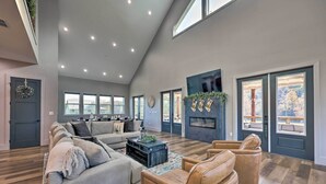 A spacious living room with a high ceiling, large windows, and a fireplace. - Lavish Riverfront Escape w/ Gas Grill! (Glenwood)
