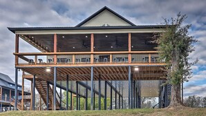 A two-story building with a wooden deck and a covered upper level. - Lavish Riverfront Escape w/ Gas Grill! (Glenwood)