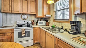 A kitchen with wooden cabinets, a stove, a microwave, a coffee maker, and a window with blinds. - Secluded Remer Cabin w/ Lake Access! (Remer)