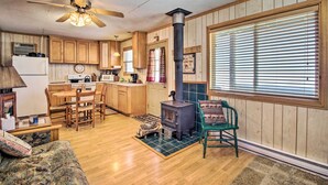 A cozy kitchen with wooden cabinets, a stove, and a dining area with a table and chairs. - Secluded Remer Cabin w/ Lake Access! (Remer)