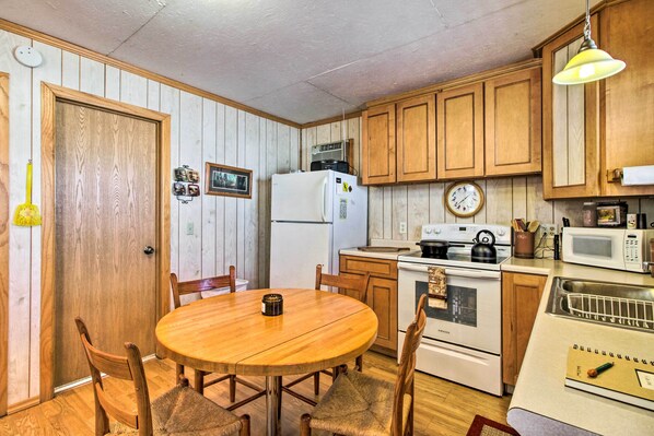 A kitchen with wooden cabinets, a refrigerator, a stove, and a microwave. - Secluded Remer Cabin w/ Lake Access! (Remer)