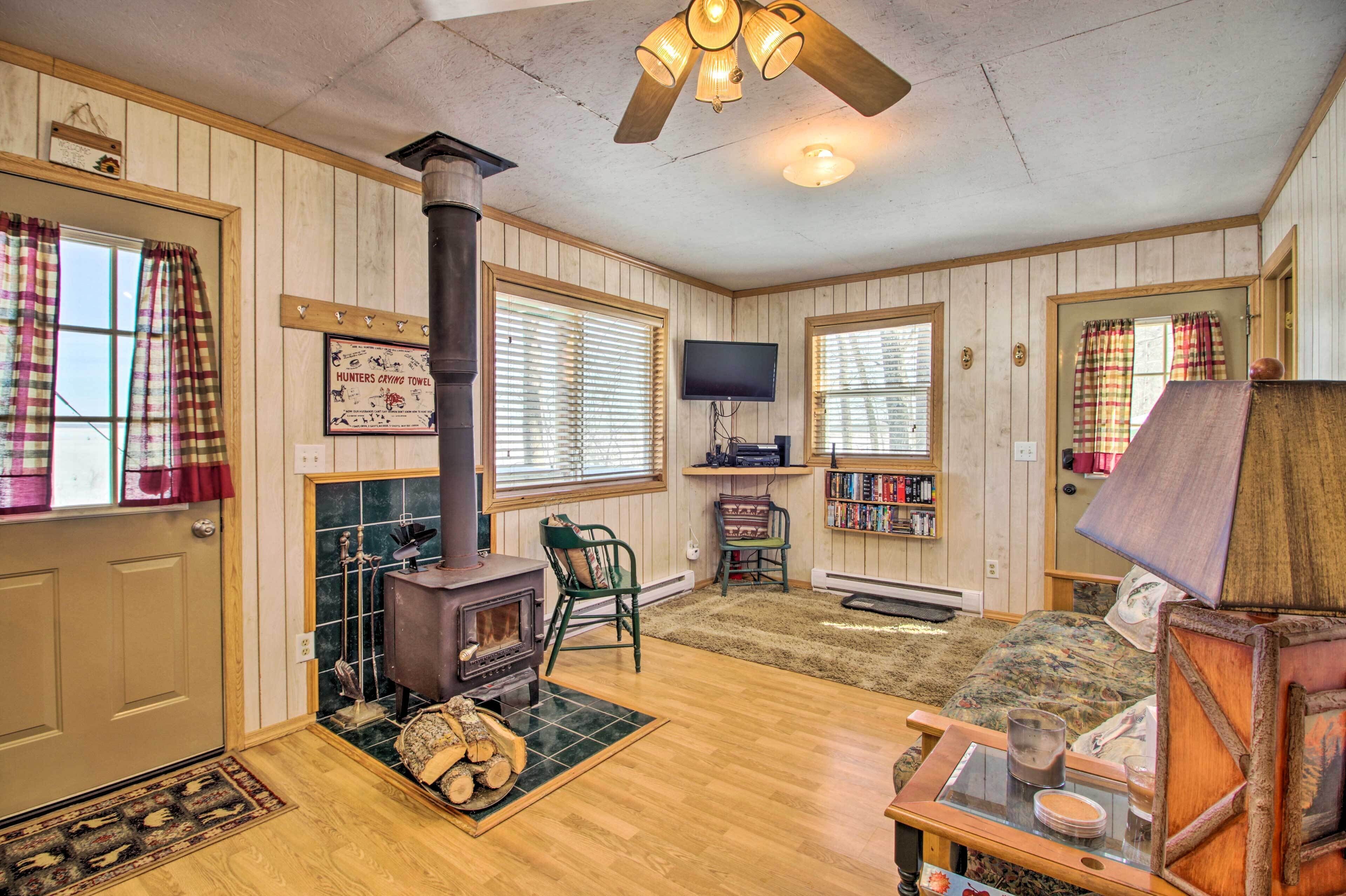 A cozy living room with a wood-burning stove, a television, and a fireplace.