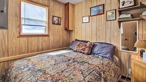 A wooden-paneled bedroom with a bed, window, and wall-mounted shelves. - Secluded Remer Cabin w/ Lake Access! (Remer)