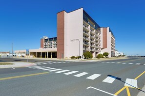 A multi-story hotel with a prominent entrance, a parking garage, and a clear blue sky.