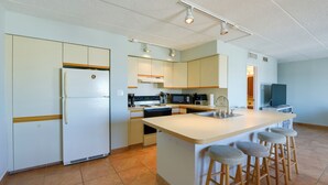 A modern kitchen with a central island, built-in appliances, and bar stools.