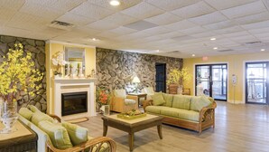 A spacious lobby with a stone wall, a fireplace, comfortable seating, and a large window.