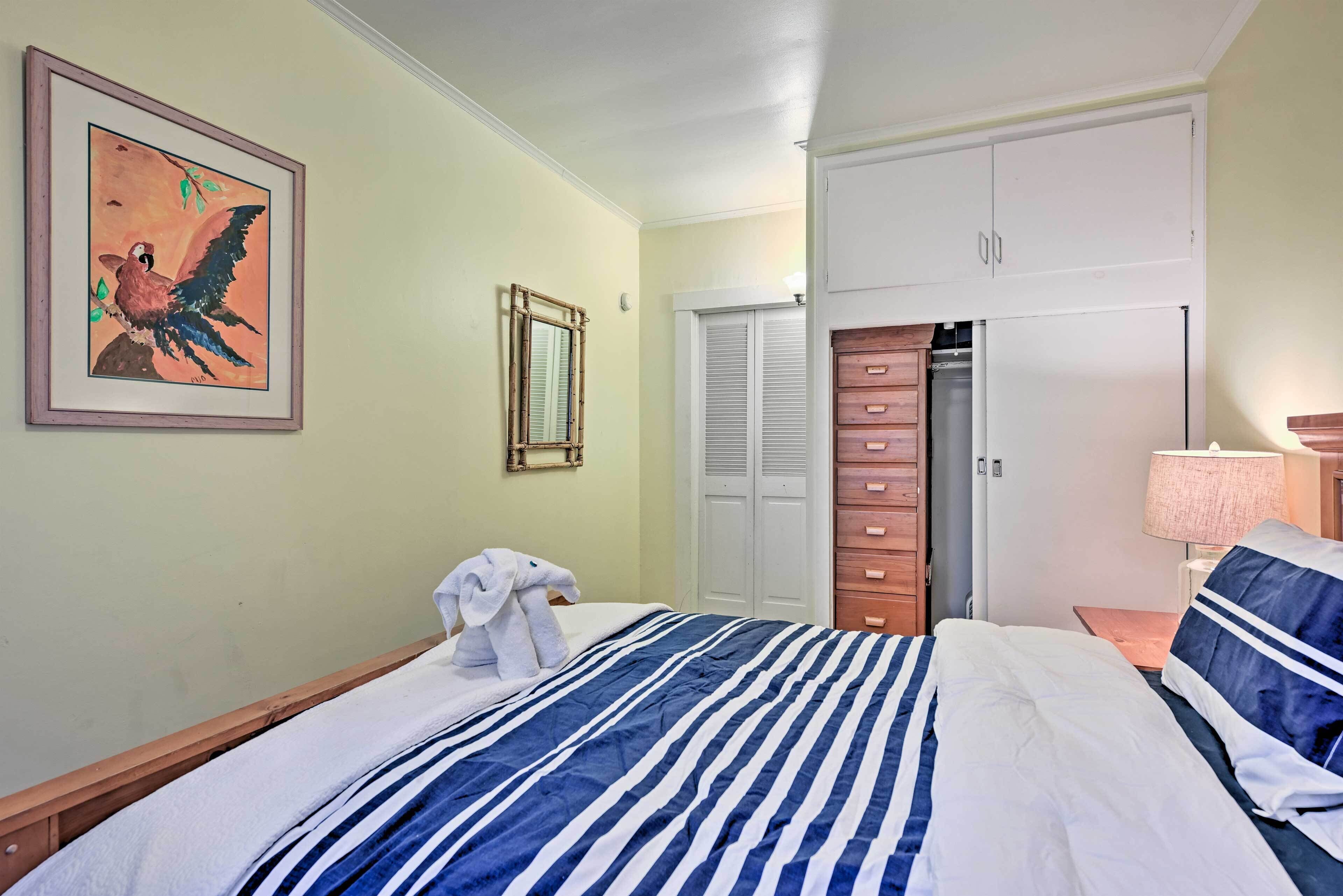 Una camera d'albergo con un letto, un armadio, uno specchio e un quadro appeso al muro.
