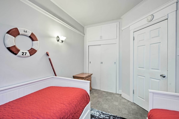 A bedroom with a bed, a nightstand, a dresser, a door, and a wall-mounted light fixture. - Steps to Avalon Bay: Sunny Catalina Island Home! (Avalon)