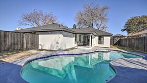 A backyard with a swimming pool, a wooden fence, and a house with a garage. - Stunning Plano Home w/ Private Pool & Hot Tub (Plano)