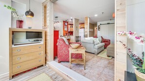 A modern living room with a TV, sofa, and red patterned armchair. - Walk to Slopes: Snowshoe Condo w/ Sunroom (Snowshoe)