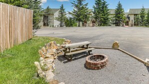 A gravel area with a wooden picnic table and a brick fire pit. - Walk to Slopes: Snowshoe Condo w/ Sunroom (Snowshoe)