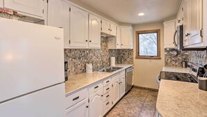 A kitchen with white cabinets, a refrigerator, a sink, and a stove.