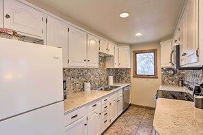 A kitchen with white cabinets, a refrigerator, a sink, and a stove.