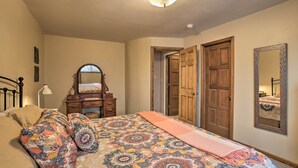 A bedroom with a bed, dresser, mirror, and two doors.