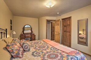 A bedroom with a bed, dresser, mirror, and two doors.