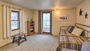 A bedroom with a bed, a small table, a bookshelf, and a window with curtains.