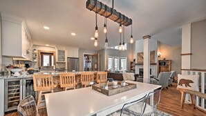 A spacious kitchen with a central island, wooden chairs, and a hanging light fixture. - Updated Condo Next to Burke Mountain Bike Trails! (East Burke)