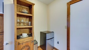 A compact kitchen with a wooden cabinet, a stainless steel refrigerator, and a trash bin. - Quaint Fredericksburg Studio w/ Shared Hot Tub (Fredericksburg)