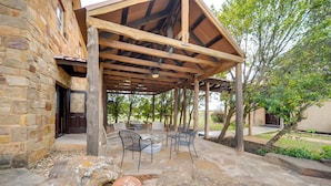 An outdoor patio with stone flooring, rustic wooden beams, and metal chairs. - Quaint Fredericksburg Studio w/ Shared Hot Tub (Fredericksburg)