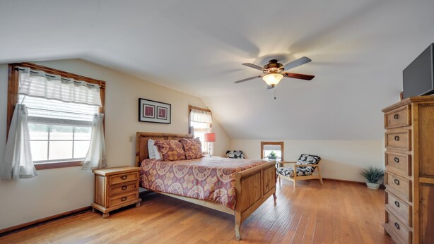 A bedroom with a wooden bed, a ceiling fan, a dresser, and a nightstand. - Quaint Fredericksburg Studio w/ Shared Hot Tub (Fredericksburg)