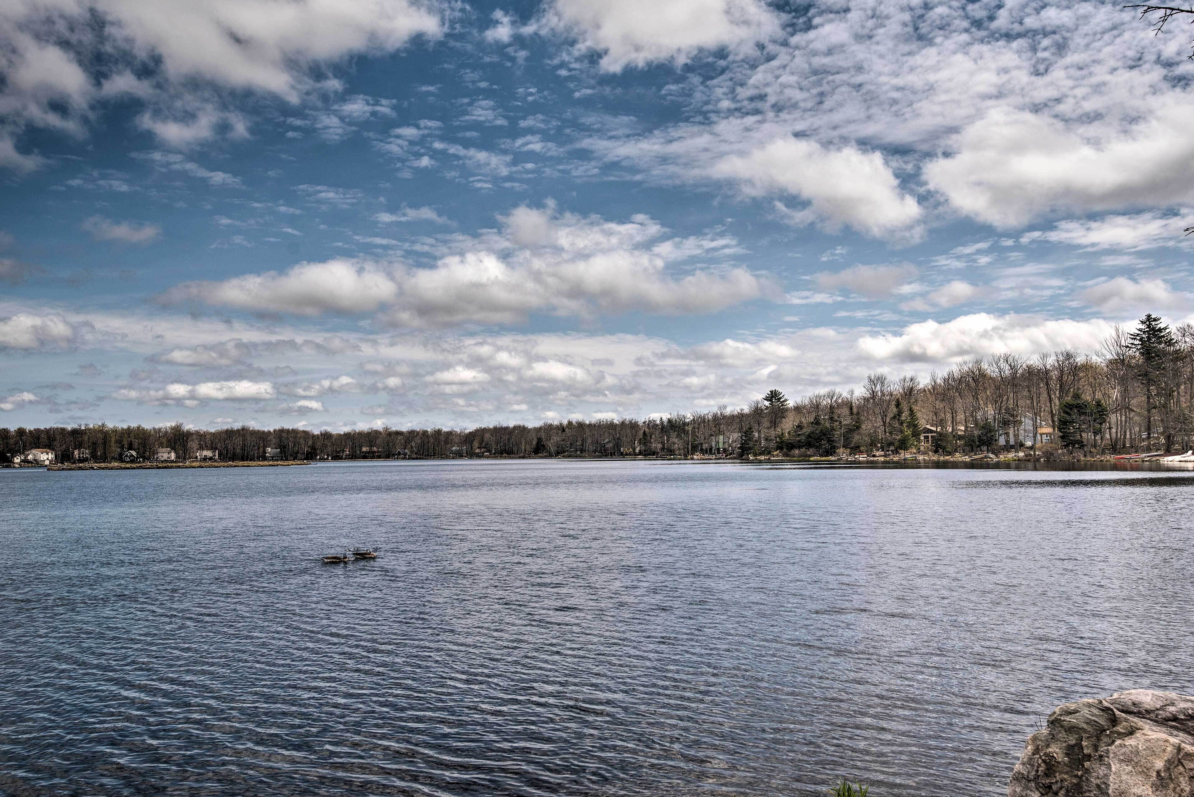 Ein ruhiger See mit einer Reihe von Häusern am Ufer und einem kleinen Boot im Wasser.