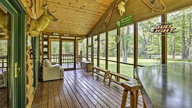 A wooden deck with a deer head decoration, a Bud Light sign, and a welcome sign for Wisconsin. - Scenic Cabin on 2 Acres Near Lake Holcombe Marina! (Holcombe)