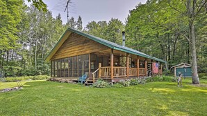 A log cabin with a porch, large windows, and an American flag. - Scenic Cabin on 2 Acres Near Lake Holcombe Marina! (Holcombe)