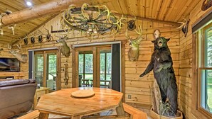 A rustic wooden cabin interior with a dining table, leather sofa, and various animal taxidermy mounted on the walls. - Scenic Cabin on 2 Acres Near Lake Holcombe Marina! (Holcombe)