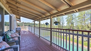 A covered wooden deck with wicker furniture and hanging planters. - Jackson Escape w/ Hot Tub & Mtn Views! (Jackson)