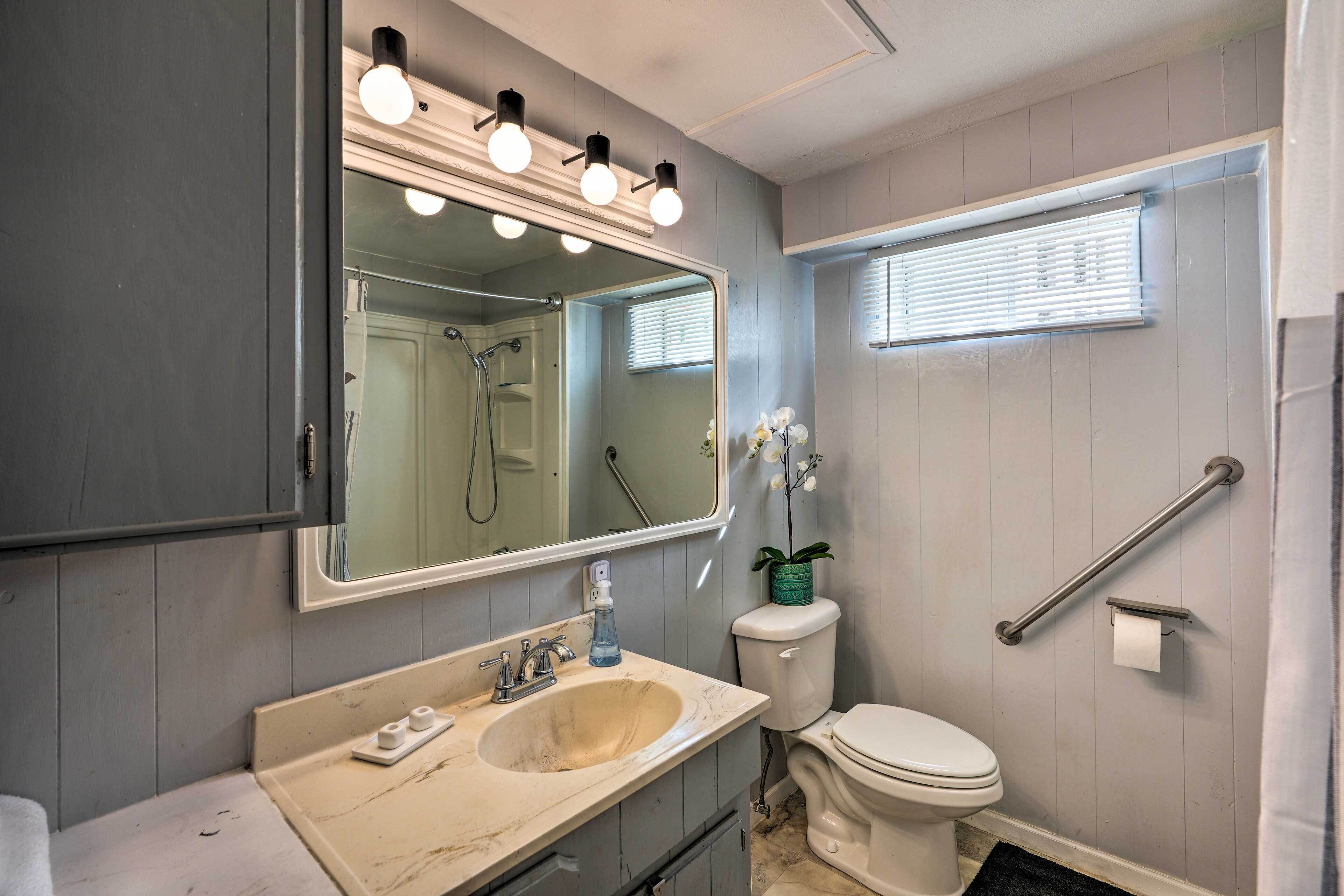 A bathroom with a sink, mirror, toilet, and shower.