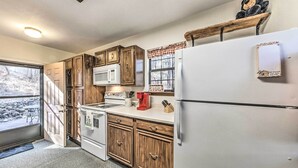 A kitchen with wooden cabinets, a white refrigerator, a microwave, and a stove.