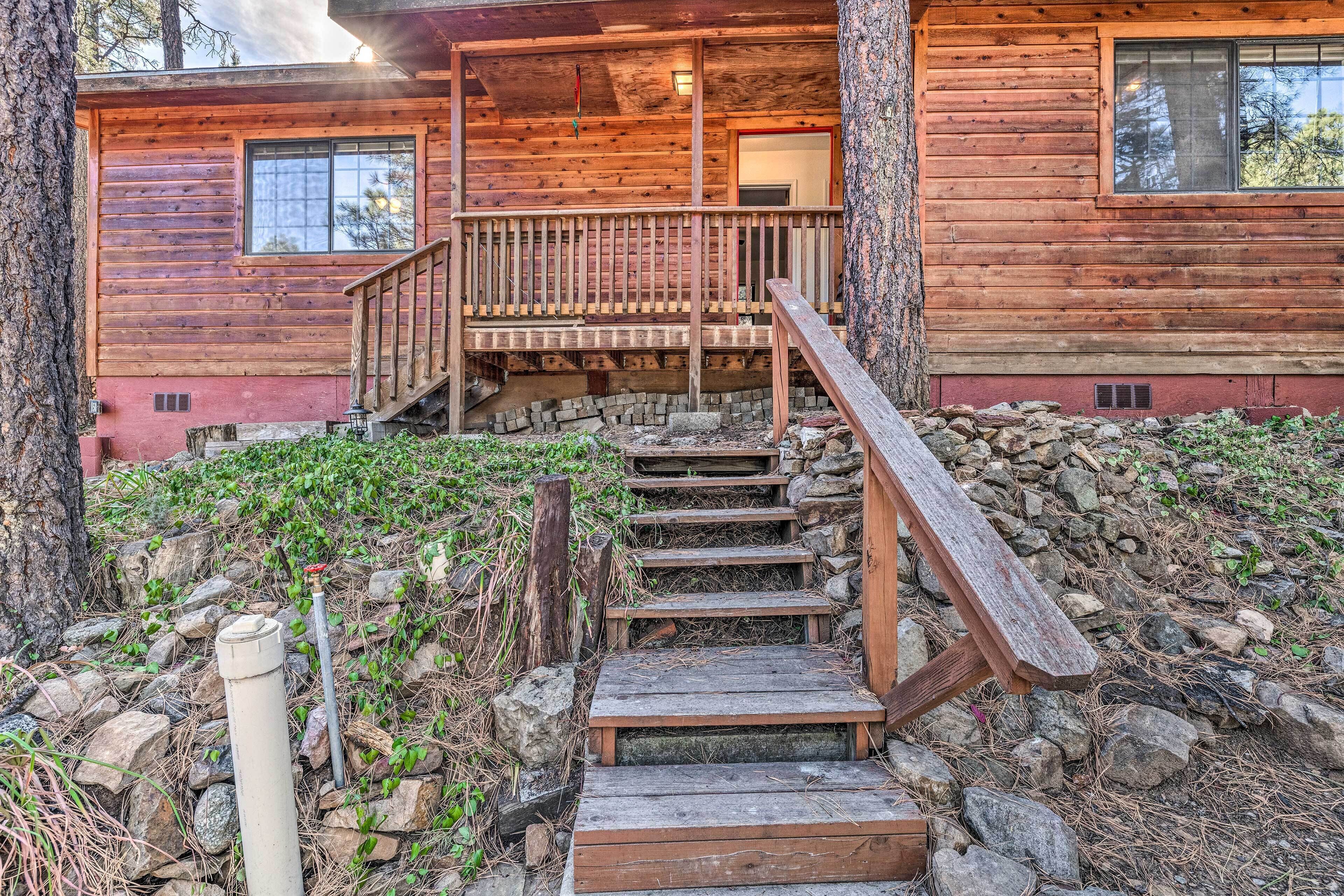 A wooden cabin with a wooden staircase leading to a porch.