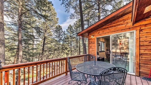 A wooden cabin with a deck, a table with chairs, and a sliding glass door.