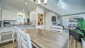 A modern kitchen with white cabinets, a wooden dining table, and a chandelier. - Sapphire Home w/ Grill & Pool Access (Sapphire)
