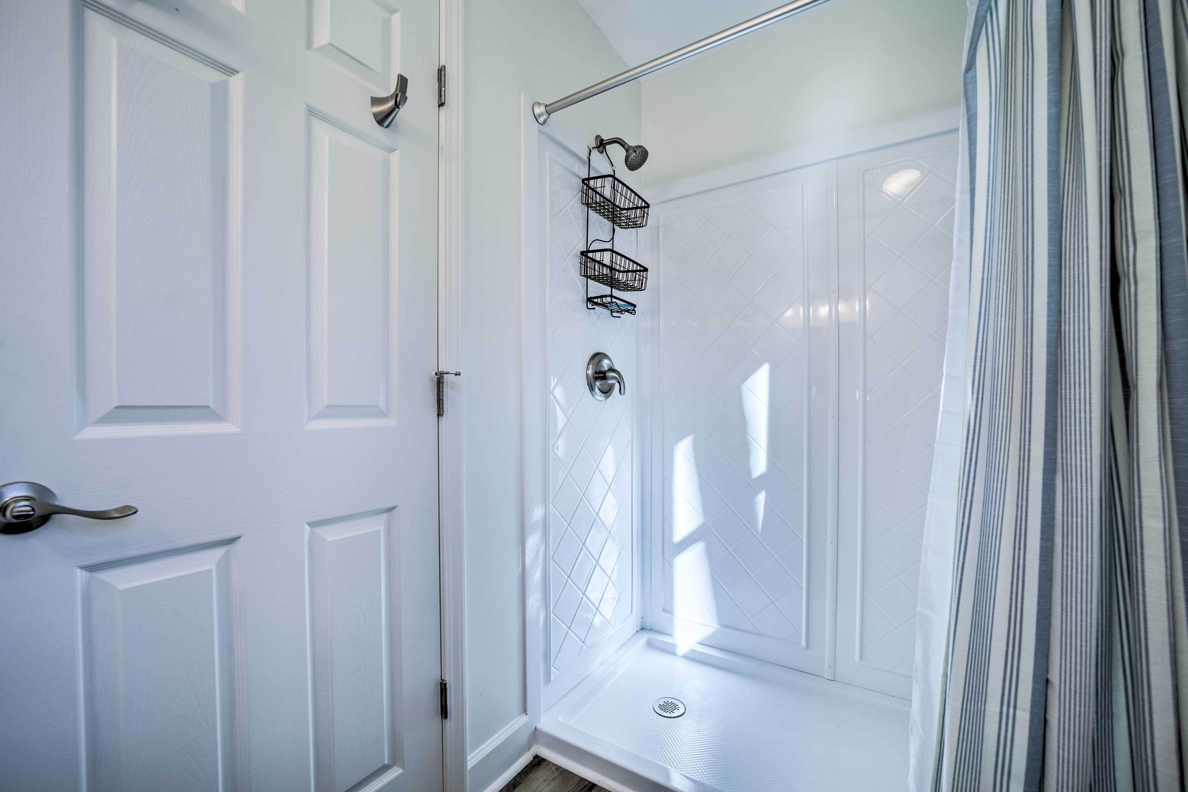 A walk-in shower with a glass door, a showerhead, and a metal towel rack.