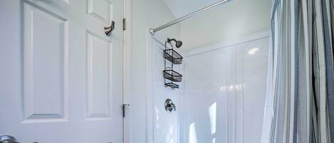 A walk-in shower with a glass door, a showerhead, and a metal towel rack.
