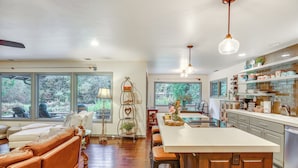A spacious living area with a large window, a sofa, and a dining table. - Fishing & Rafting: Mckenzie River Cabin! (Blue River)